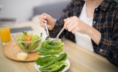 Happy beautiful Asian woman eating healthy food with vegan.salad in the kitchen at home.