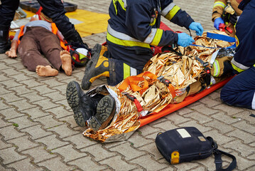 Rescuers provide first aid to the victim during a car accident. Person injured in the accident is lying on the road