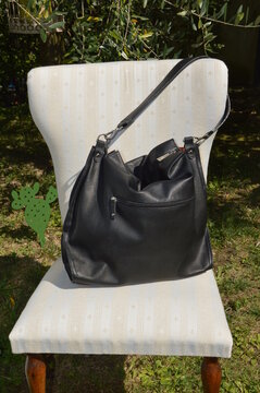 Black leather bag displayed on a chair. 