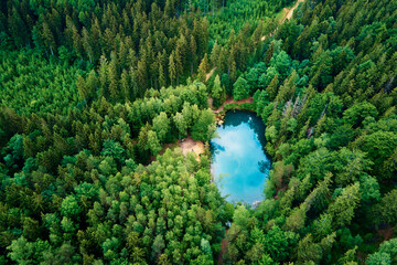 Blue lake in the middle of green forest, aerial view. Wild colorful lake in mountain park in Poland. Beautiful nature landscape