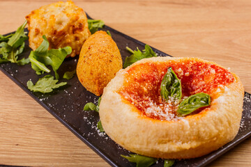 Tris di antipasti fritti di una pizzeria napoletana. Una montanara con sugo di pomodoro, formaggio e basilico, un crocchè di patate con provola filante e una frittata di pasta