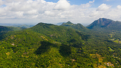 Fototapeta premium Mountains covered rainforest, trees and blue sky with clouds. Sri Lanka.