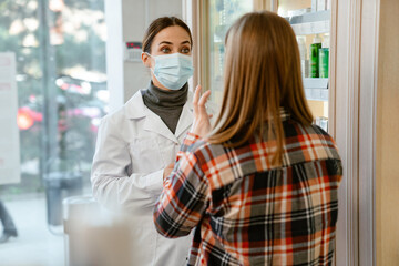 White apothecary wearing face mask working with customer