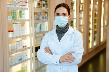 White apothecary wearing lab coat and face mask working in pharmacy