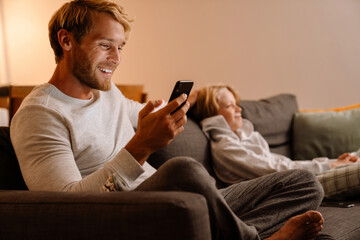 White father and son using cellphone and watching tv at home
