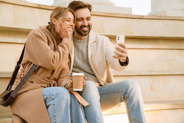 White couple laughing and taking selfie on cellphone during date