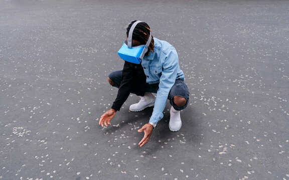Man wearing virtual reality headset crouching on road