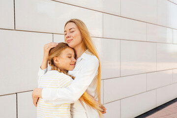 Happy mother hugging daughter in front of wall