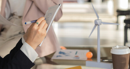 Businesswoman writing on note pad with pen in office