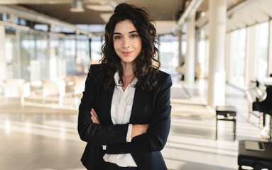 Confident businesswoman with arms crossed standing at office