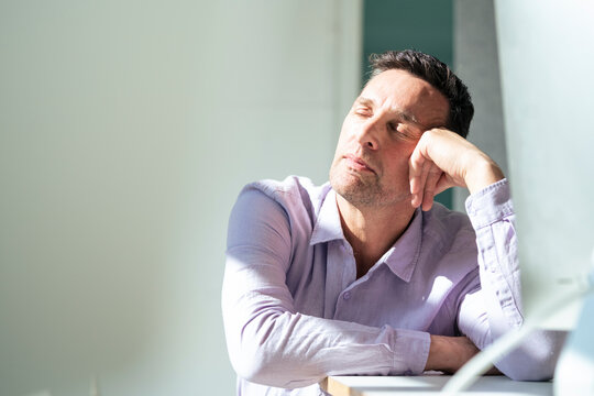 Mature businessman taking nap at desk in office