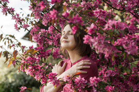 Smiling woman with eyes closed standing amidst pink flowers