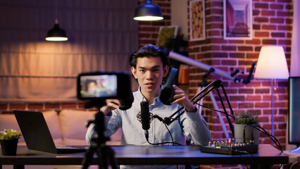 Asian influencer filming headphones review on podcast episode, recording recommendation video on...