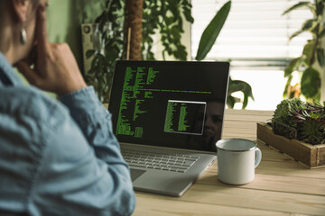 Freelancer with laptop and coffee cup at table in home office