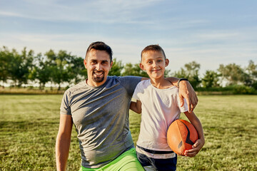 Happy father and son together st sports field on sunny day