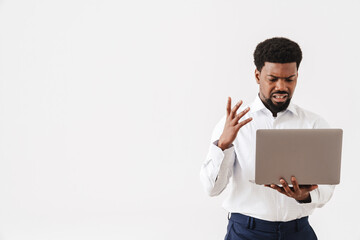 Black displeased man gesturing while working with laptop