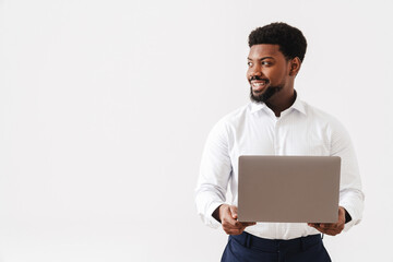 Black bearded man wearing shirt smiling and working with laptop