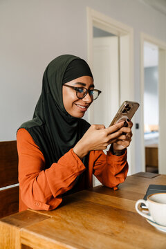 Young Beautiful Smiling Woman In Hijab Looking On Her Phone
