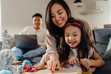 Happy asian family sitting on sofa in cozy living room