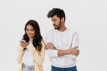 Naklejka premium East asian young man and woman smiling and using cellphone together