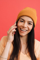 Young excited girl wearing hat posing at camera with cellphone