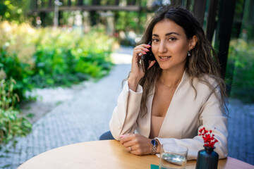 Young brunette business woman talking on the smart phone in street cafe of Prague