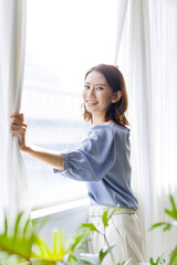 カーテンを開ける女性