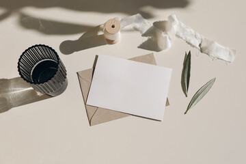 Summer Mediterranean stationery still life. Dark glass, cocktail drink with olive tree leaves in...