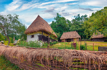 Fototapeta na wymiar Wooden fence in Romanian village with traditional peasant houses. Wonderful rural scene of Transylvania, Romania, Europe. Beauty of countryside concept background.