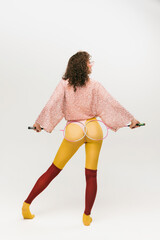 Back view of young fashionable girl in avant-garde style outfit over white background. Vivid style,...
