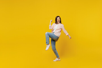 Fototapeta na wymiar Full body young happy smiling woman she 30s wear striped shirt white t-shirt doing winner gesture celebrate clenching fists say yes isolated on plain yellow background studio People lifestyle concept