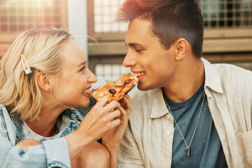 food and people concept - happy young couple eating takeaway pizza outdoors