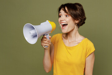 Young excited fun woman she 20s wear yellow t-shirt hold scream in megaphone announces discounts sale Hurry up isolated on plain olive green khaki background studio portrait People lifestyle concept