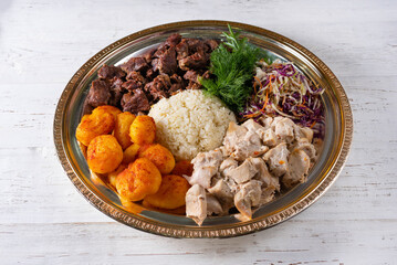 meat, potatoes, rice and salad. on a white wooden background