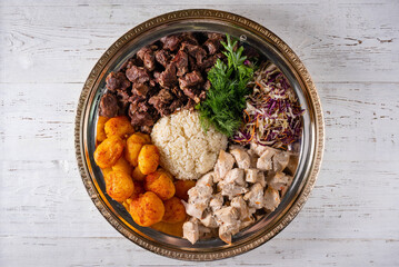 meat, potatoes, rice and salad. on a white wooden background