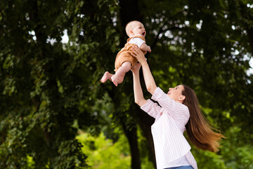 Photo of cheerful positive mother little son dressed casual clothes catching arms playing enjoying sunshine outdoors backyard