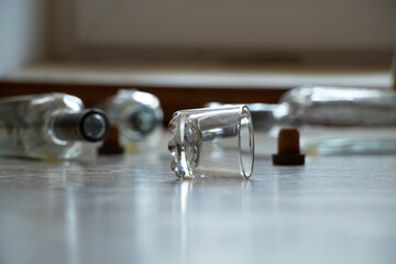 A glass and empty alcohol bottles lie on the floor in an apartment in the dark, alcoholism and bad habits, glass bottles and a glass
