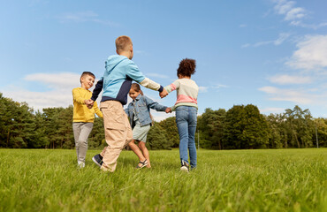 Obraz premium childhood, leisure and people concept - group of happy kids playing round dance at park