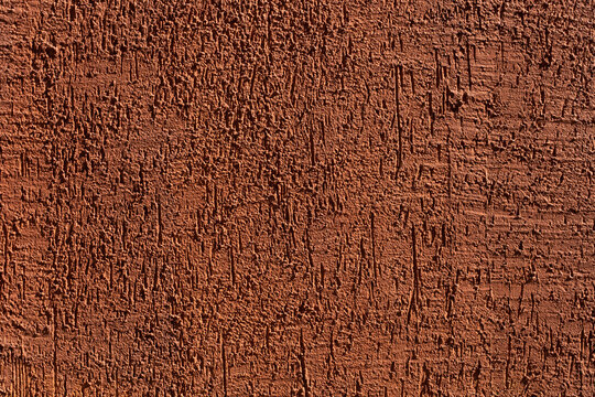 Grunge texture wall. Plaster bark beetle in bright terracotta color. Facing and plastering of buildings.