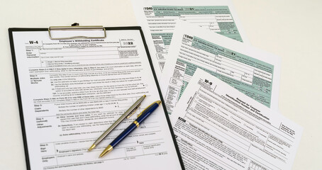Fototapeta premium top view of tax forms on tablet on office desk with calculator and pen.