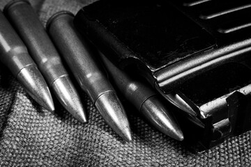 Ak-47 (7,62x39mm) ammunition being loaded to magazine, military canvas background, monochrome photo