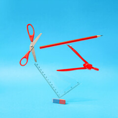 Creative surreal composition with red school supplies against pastel blue background. Back to school.