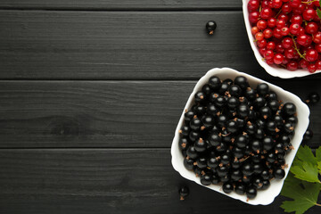 Bowls with ripe red and black currant on black background.