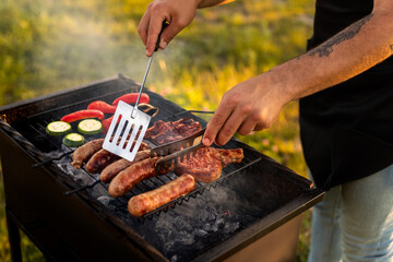 Crop man grilling meat and vegetables during barbecue