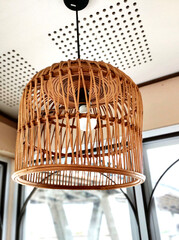 hanging indoor bulb lamp in a bird cage model rattan basket  ( keranjang rotan ) as a decoration lamp in a cafe. Interior design.