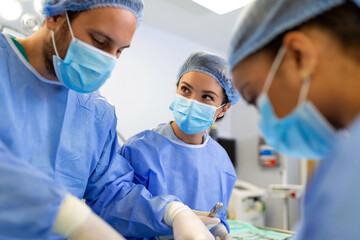 Surgeons in a light operating room perform plastic surgery, a team of male and female doctors perform reconstructive surgery.
