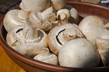 Fresh champignon mushrooms on a ceramic plate, close-up.