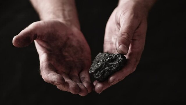 A miner shows the pieces and nuggets of coal in his hands.