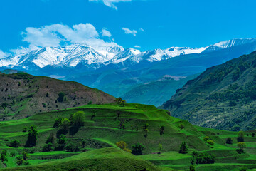 landscape of mountainous Dagestan with terraced fields and snowy peaks in the distance