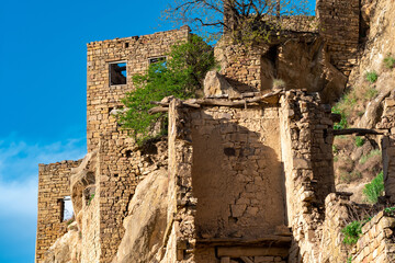 ruins of stone houses attached to the rock in the depopulated village of Gamsutl in Dagestan